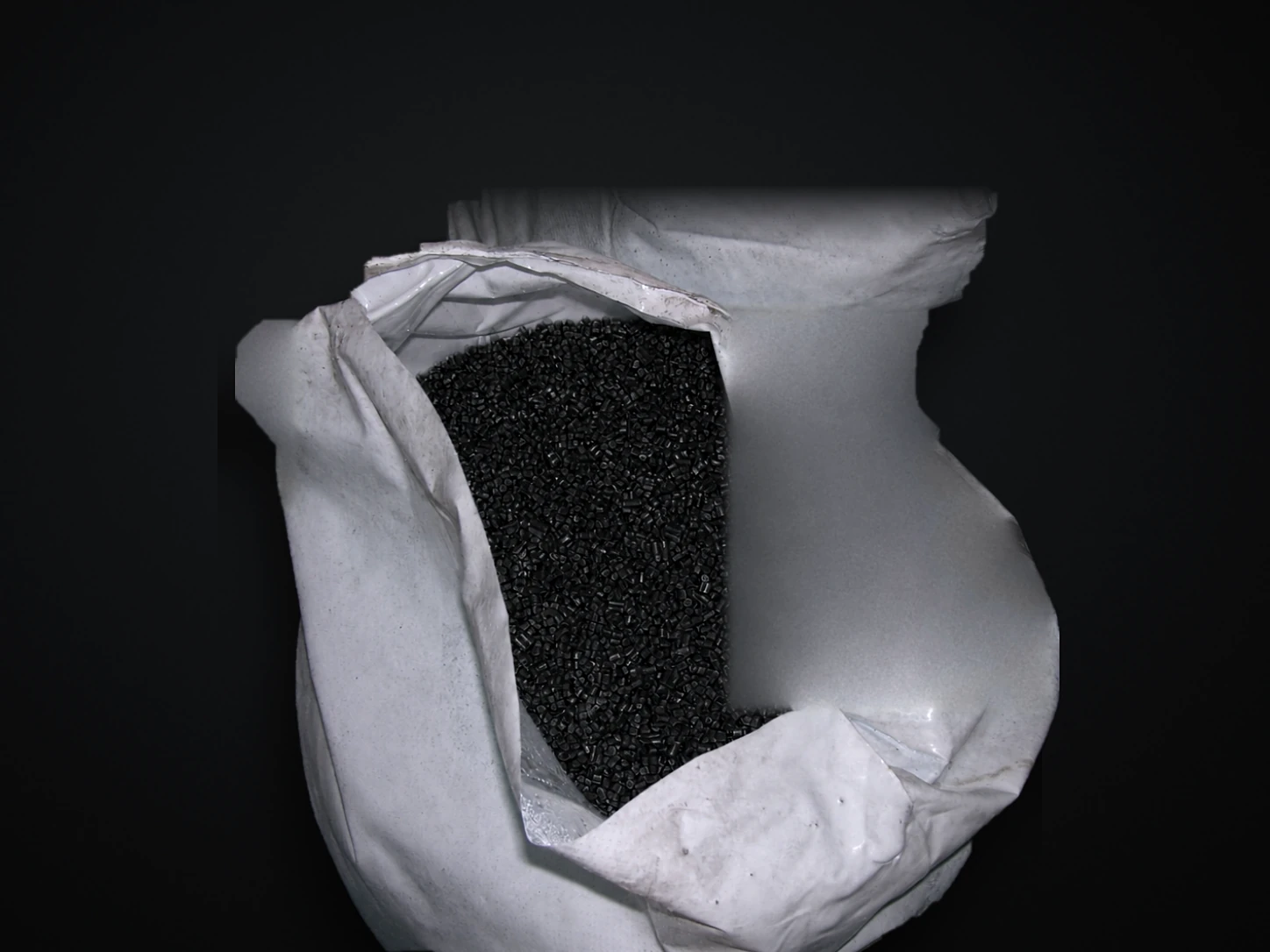 Production photograph of black masterbatch pellets in an open industrial bag